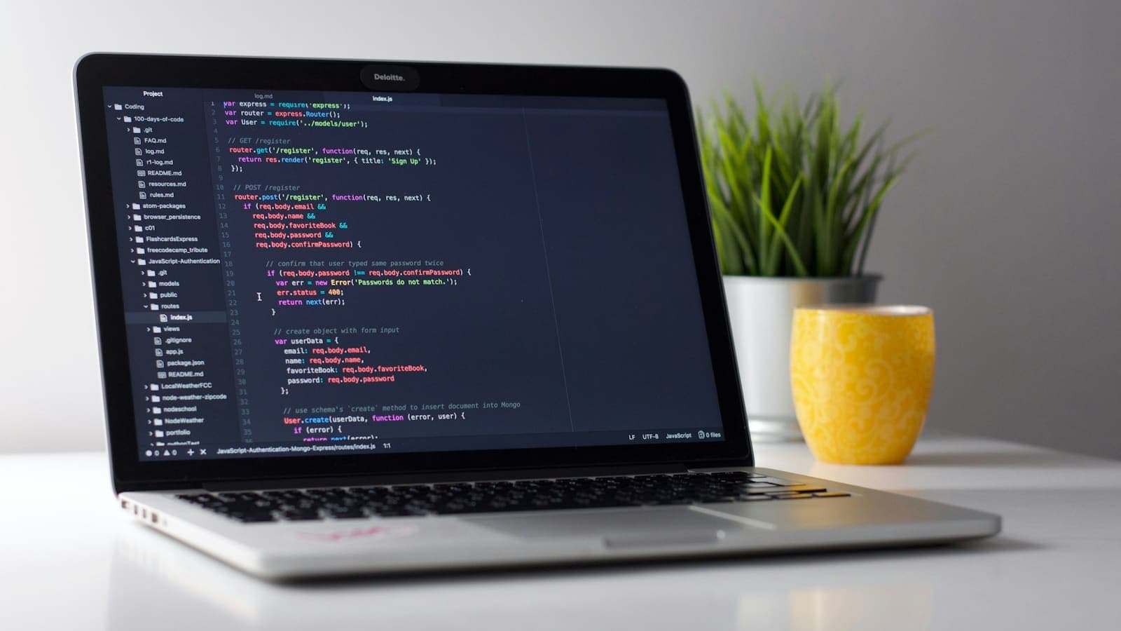 A laptop on a white desk with code open in an editor