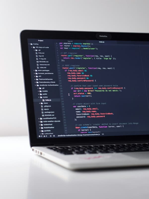 A laptop on a white desk with code open in an editor